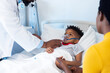 © WavebreakMediaMicro - African american male doctor giving ventilator to boy patient with mother in hospital and copy space