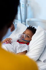 Wall Mural - African american son patient in hospital ventilator mask, looking to mother with copy space