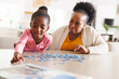 © Wavebreak Media - Happy african american grandmother and granddaughter doing puzzle
