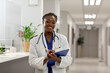 © Wavebreak Media - Portrait of happy african american female doctor working at hospital, holding clipboard