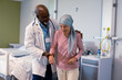 © Wavebreak Media - African american male doctor visitng senior caucasian female cancer patient in head scarf