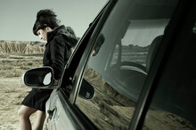 Young Woman Sitting In The Front Part Of A Car In Reflexive Attitude, Bardenas Reales, Navarra, Spain