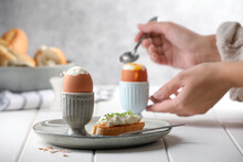 Woman Eating Breakfast With Fresh Soft Boiled Egg At White Wooden Table, Focus On Plate