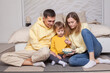© artmim - Cute family, parents in yellow clothes with child son sitting by the bed and eating popcorn
