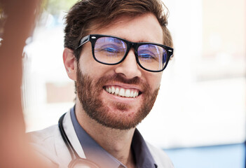 Doctor, man and selfie with smile at hospital for social media app, profile picture and happy with glasses. Medic, happiness and workplace digital photo for blog, internet or web networking in clinic