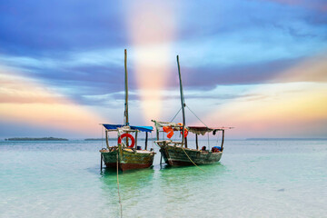 Wooden fisherman boats on sandy beach with blue water background, Zanzibar, Tanzania