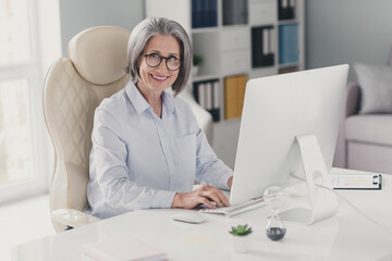 Sticker - Photo of successful smart aged lady lawyer sitting leather chair keyboard write email coworking office inside