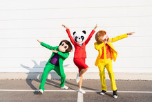 Playful Friends Wearing Animal Masks Dancing In Front Of Wall