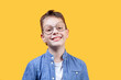 Portrait of a boy with glasses smiling and looking at camera. Headshot. Yellow background. Front view. Copy space. Suitable for collage and banner making and other design