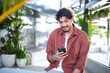 © Austockphoto - Man smiling on mobile phone in open room with plants