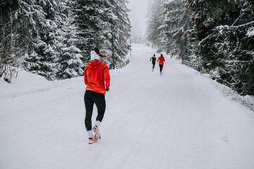 Wall Mural - Female runners pound the snowy trails, their breath visible in the crisp mountain air of a snowy forest