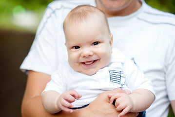 baby smiling and looking up to camera outdoors in sunlight