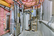 Unfinished basement mechanical room with condensing tankless water heater, storage tank, plumbing and heating systems