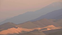 Telephoto Landscape Of Massive Sand Dunes With Mountain Range Behind