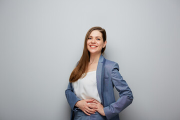 Wall Mural - Smiling business woman in blue suit. Female portrait near gray wall.