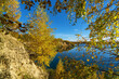 Blue lake in the distance through yellow leaves in autumn.