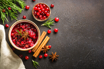 Wall Mural - Cranberry sauce in a bowl with rosemary and spices. Top view at black background.