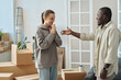 © AnnaStills - Happy girl getting keys from her new apartment from real estate agent, they standing in the room among packed boxes