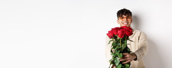 Handsome boyfriend giving you bouquet of roses, make surprise gift on romantic date at valentines day, standing with lover over white background