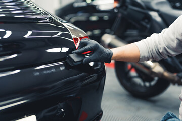 close-up shot of unrecognisable man wearing black gloves applying ceramic coating to car using spong