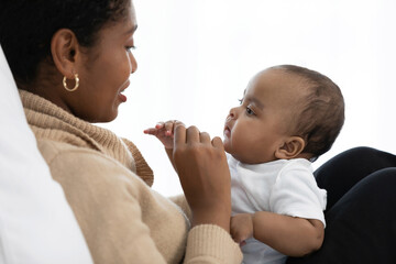 Wall Mural - African young mother playing with her adorable baby on bed