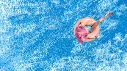 Wall Mural - Beautiful woman in hat in swimming pool aerial top view from above, young girl in bikini relaxes and swims on inflatable ring donut and has fun in water on tropical vacation on holiday resort
