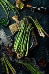 Wall Mural - Cooking asparagus. Green asparagus with spices on the table. Healthy food. On a stone background. Top view.