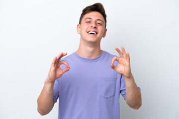 Young handsome Brazilian man isolated on white background showing ok sign with two hands