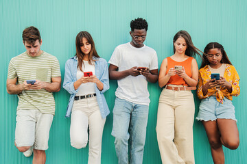 group of multiethnic teenagers addicted to use the smartphone on blue background. five multiracial y