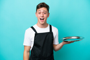 Wall Mural - Young waitress with tray isolated on blue background with surprise facial expression