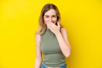 Wall Mural - Blonde English young girl isolated on yellow background happy and smiling covering mouth with hand