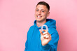 Young Brazilian man holding invisible braces isolated on pink background with happy expression