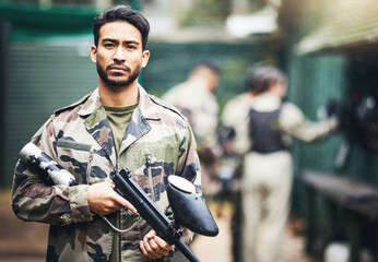 Wall Mural - Portrait, paintball and camouflage with a sports man holding a gun for a game or competition. Fitness, exercise and serious with a male athlete carrying a weapon or marker for military training