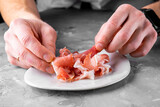 Fototapeta Kawa jest smaczna - man chef hand takes Prosciutto crudo, parma ham