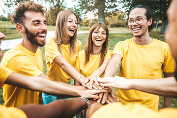 Multi ethnic young people team stacking hands together outside - International university students support and help each other - Friendship, team building, human relationship and diversity concept