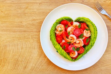 Wall Mural - 
Heart shaped avocado with roasted shrimps,cherry tomatoes and parleys on plate with wooden background.Love healthy food concept for Valentine's day.Top view.Copy space