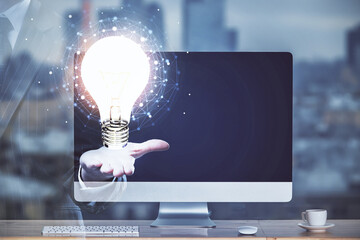 Poster - Computer on desktop in office with bulb icon hologram. Multi exposure. Concept of idea.