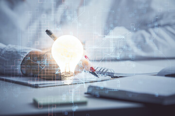 Poster - Bulb hologram over hands taking notes background. Concept of idea. Double exposure