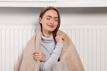 Poster - Woman with blanket sitting near heating radiator indoors