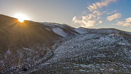 Poster - Aerial view of a dirt road Road up a mountain in winter at sunrise.