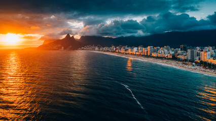 Aerial drone view of Ipanema Beach in Rio de Janeiro, Brazil at sunset with the iconic Two Brother mountains in the background