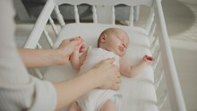 Cute Newborn Baby Sleeping Peacefully In The White Wooden Cradle While Mother Gently Stroking Baby's Belly. Slow-motion