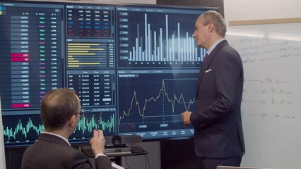 Man presenting business growth statistics on digital screen. Data engineer analyzing big data, leading conference in meeting room, talking with colleague, developing strategy. Teamwork concept