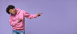 © insta_photos - Happy funny African American teen guy pointing fingers aside advertising new promo offer. Smiling black student model showing presenting ads standing isolated on purple background.