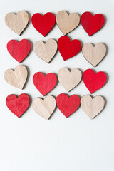 Canvas Print - array of plain and painted red wooden hearts on blank paper