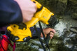 © Cavan Images - Drilling holes in rock in order to bolt in anchors for rappel station.