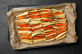 Fototapeta Kawa jest smaczna - Tray with baked parsnips and carrots on black table, top view