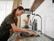 © SHOTPRIME STUDIO - Woman smiling with teeth hands without gloves washes dishes with a dishwashing sponge, household chores, no dishwasher, high water consumption. Stylish kitchen design