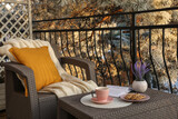 Fototapeta Kawa jest smaczna - Cup with tasty cocoa, cookies and book on rattan table at balcony