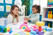 © Krakenimages.com - Teacher and toddler playing with toys sitting on table at kindergarten